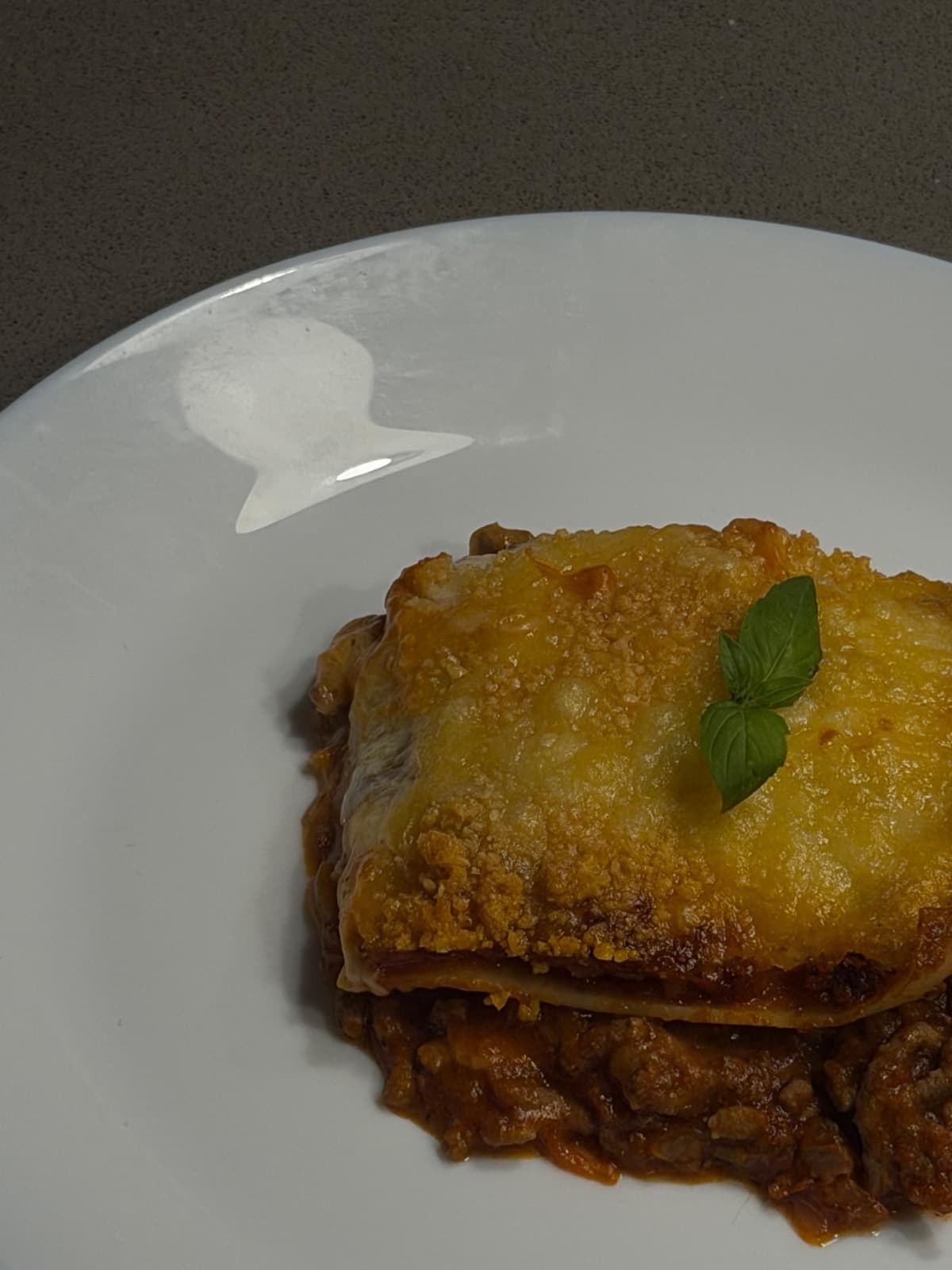 Porción de lasaña en capas con queso gratinado y salsa de tomate.